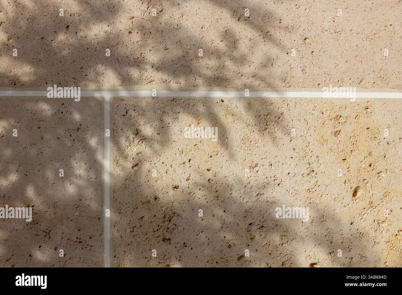 Pareti piastrellate in travertino beige, mattoni di pietra calcarea naturale alla luce del sole con ombra, sfondo per sfondi o design di striscioni Web Foto Stock