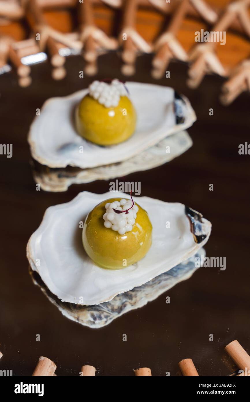 Le ostriche di cozze ricoperte di delicato gel dashi e adornate con perle di cocco offrono un'esplosione unica di umami. Una delizia gourmet che stuzzica il sen Foto Stock