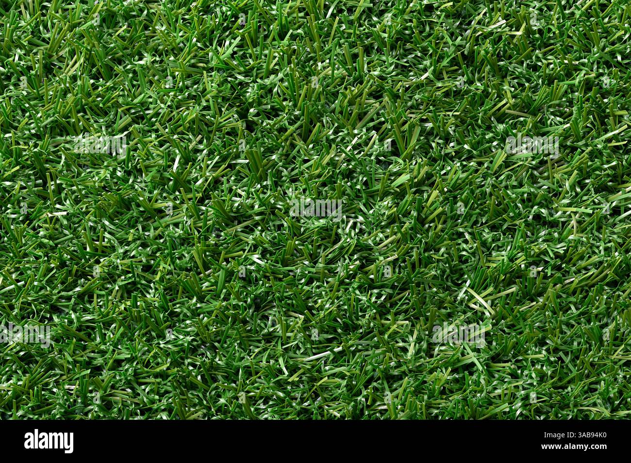 Erba sintetica verde, erba di plastica, primo piano della superficie. Superficie di colore verde di fibre sintetiche creata per sembrare erba naturale. Foto Stock