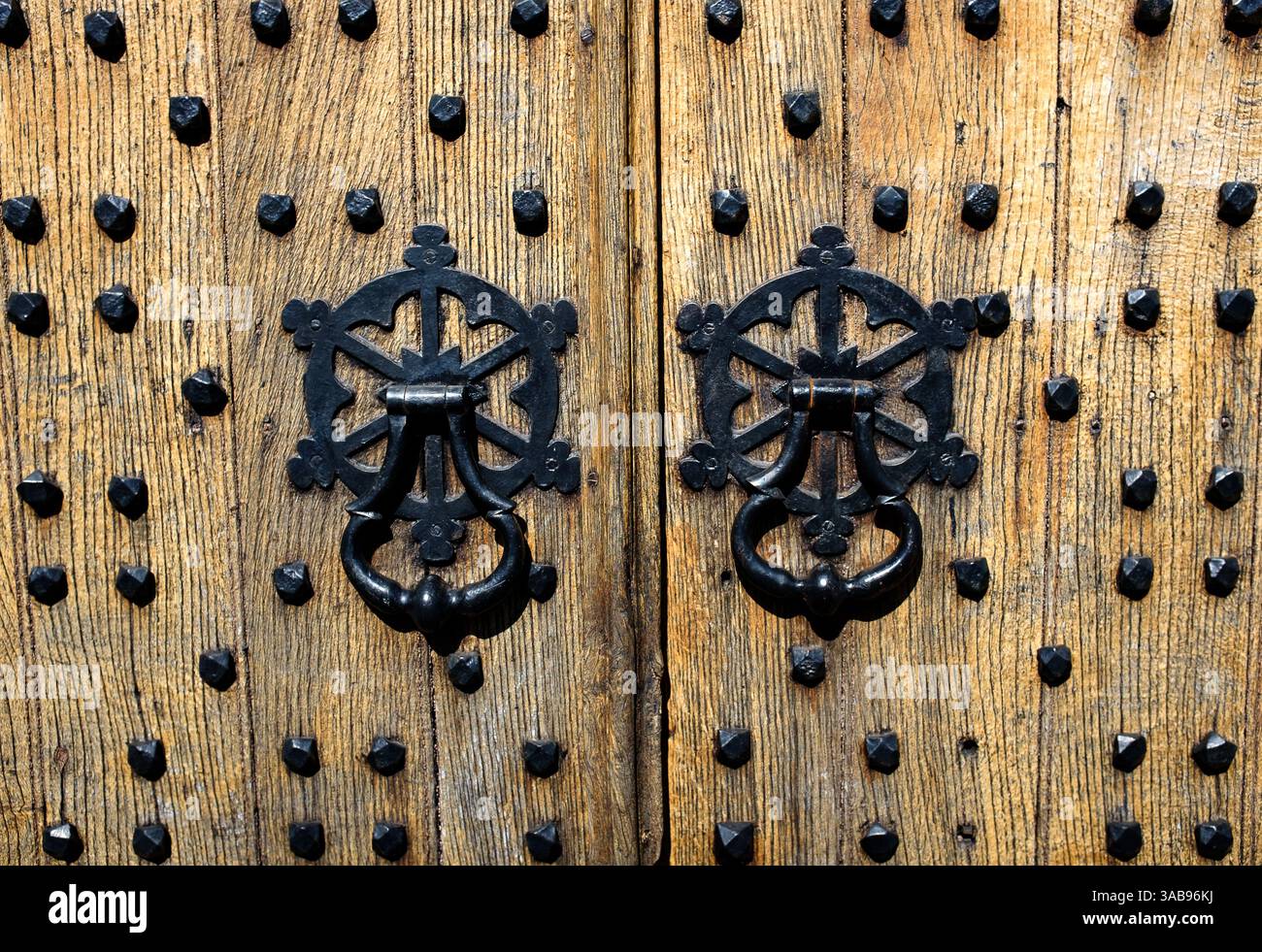 Le maniglie e i rivetti su un'antica porta in legno della chiesa di St Mary, Charlton Kings, Cheltenham, Inghilterra Foto Stock