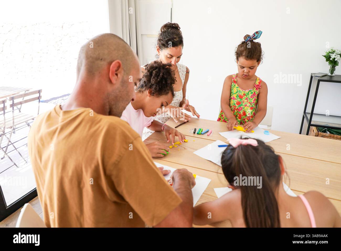 Una famiglia impegnata in attività artistiche a casa, creando disegni colorati insieme. L'ambiente accogliente e i gruppi diversificati mettono in risalto la gioia di spendere qualcosa Foto Stock