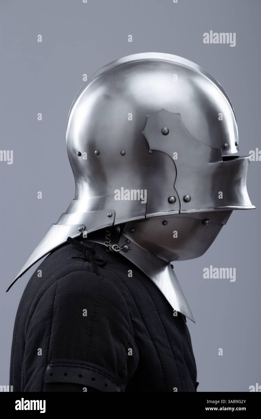 Casco medievale con visiera e biberon. L'elmetto medievale color argento lucido è dotato di visiera incernierata che può essere sollevata e di una protezione antisbandamento Foto Stock