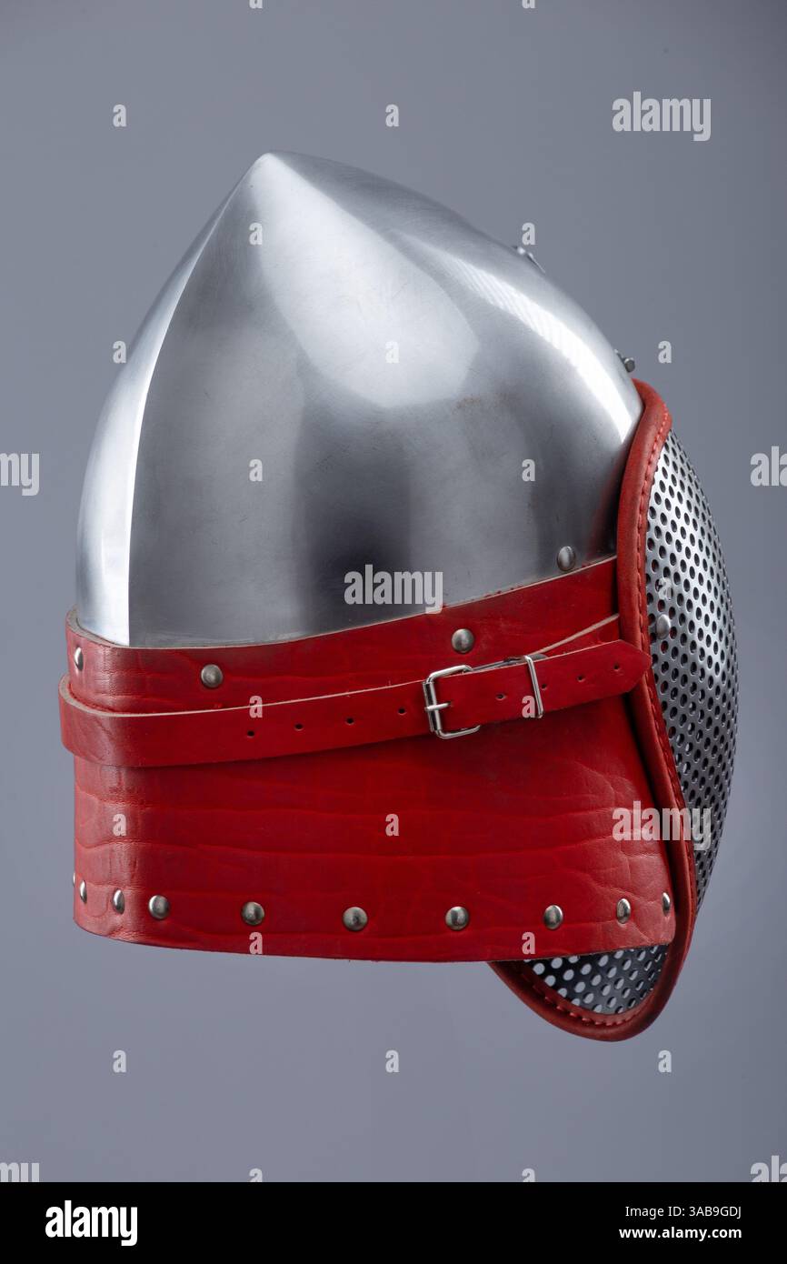 Moderno casco da scherma con visiera protettiva in rete. Un casco in argento lucido è dotato di visiera integrale in mesh ed è fissato con un cinturino in pelle rosso e me Foto Stock