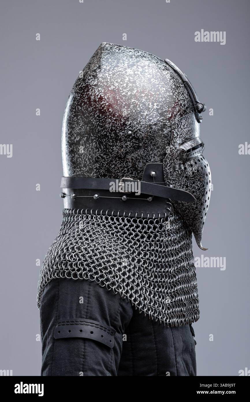 Elmetto in metallo scuro con parte superiore a punta e frontalino. Questa immagine mostra un casco in metallo scuro con una parte superiore appuntita e una mascherina che copre la parte inferiore o Foto Stock