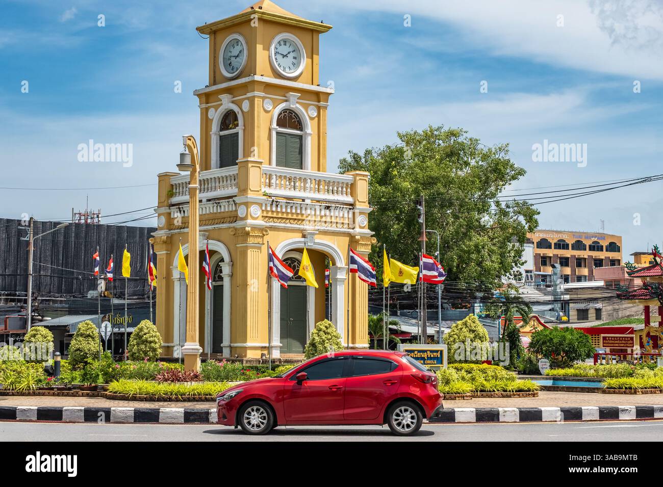 Auto rossa che guida alla rotatoria nella città vecchia di Phuket in Thailandia durante la giornata estiva. Traffico stradale alla Torre dell'Orologio Surin Circle . Arciite sino-portoghese Foto Stock
