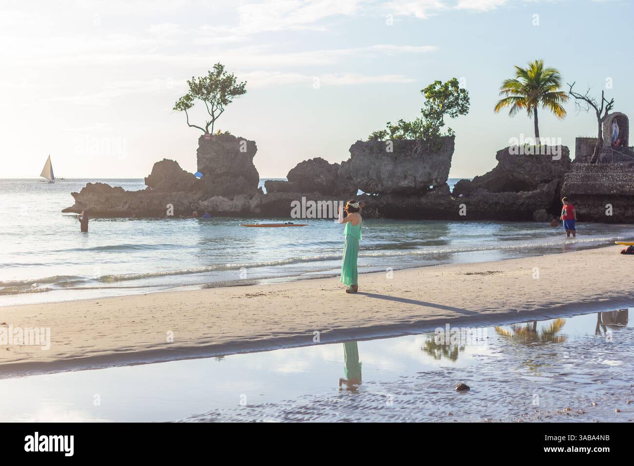 Una donna turistica saluta l'alba vicino a Willy's Rock sulla White Beach di Boracay, momenti tranquilli in uno dei luoghi più rappresentativi delle Filippine Foto Stock
