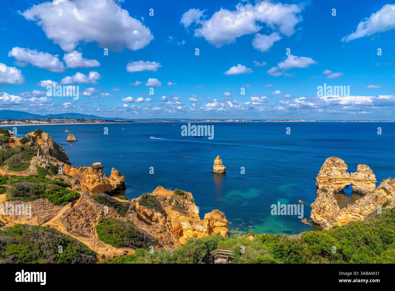 Vista della costa dell'Algarve del Portogallo vicino alla città di Lagos, con il mare cristallino e le formazioni rocciose dorate Foto Stock