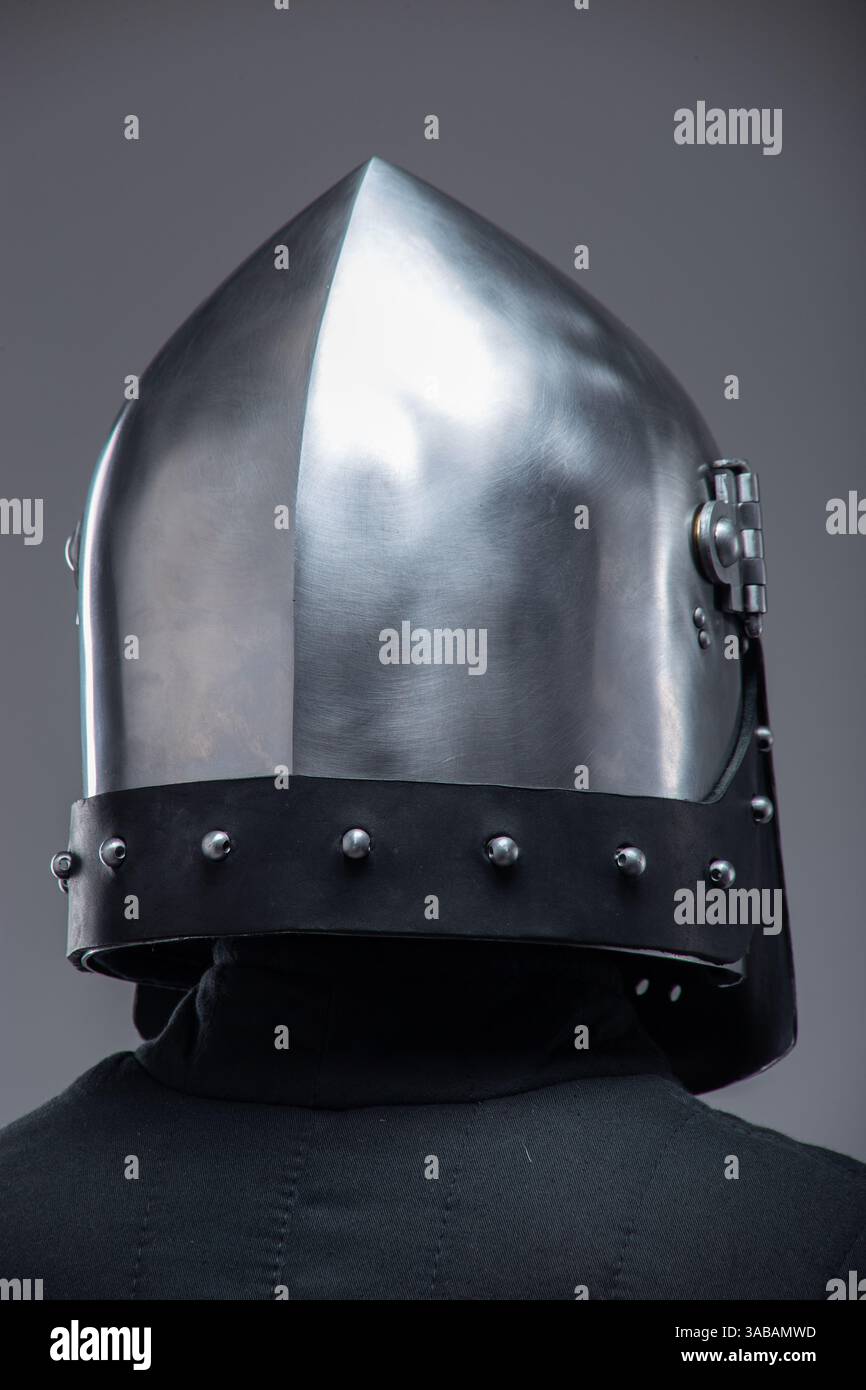 Primo piano del casco di un cavaliere medievale con visiera perforata. Questa immagine si concentra su un casco in metallo lucido con numerosi piccoli fori nella visiera, indossato Foto Stock