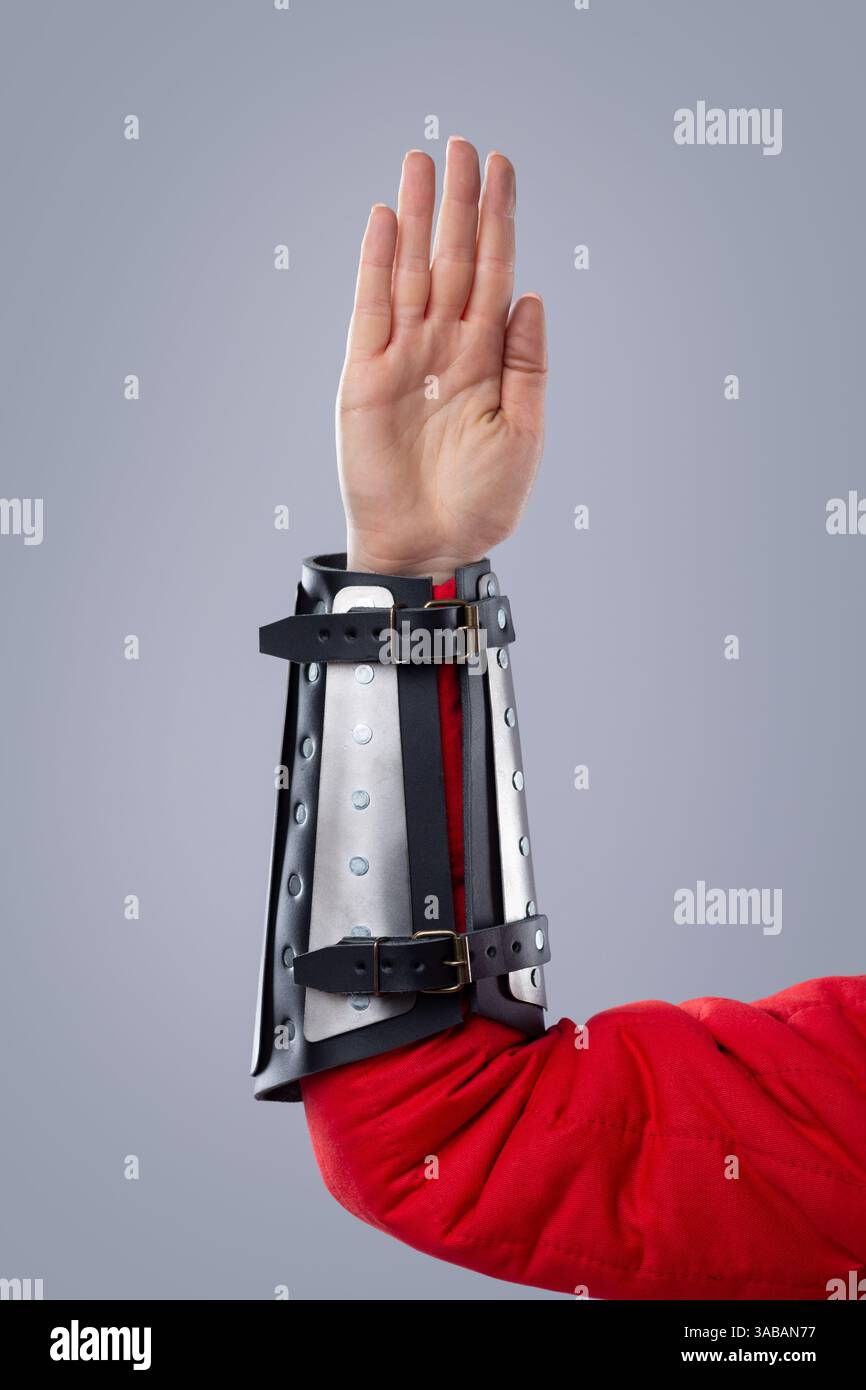 Primo piano di bracciali con spillatura d'argento su armatura rossa imbottita. Questa immagine mostra un primo piano di rinforzi in metallo argentato indossati su un indumento imbottito rosso, Foto Stock