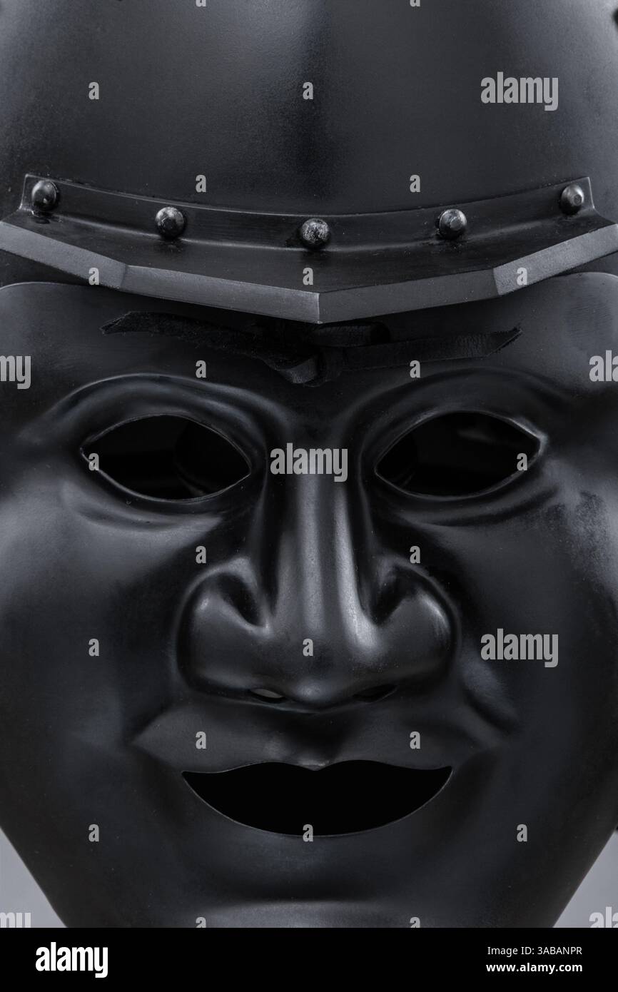 Casco Dark Samurai con maschera facciale minacciosa. Questa immagine presenta un casco samurai scuro, quasi nero, con una maschera facciale dettagliata che mostra un ex feroce Foto Stock