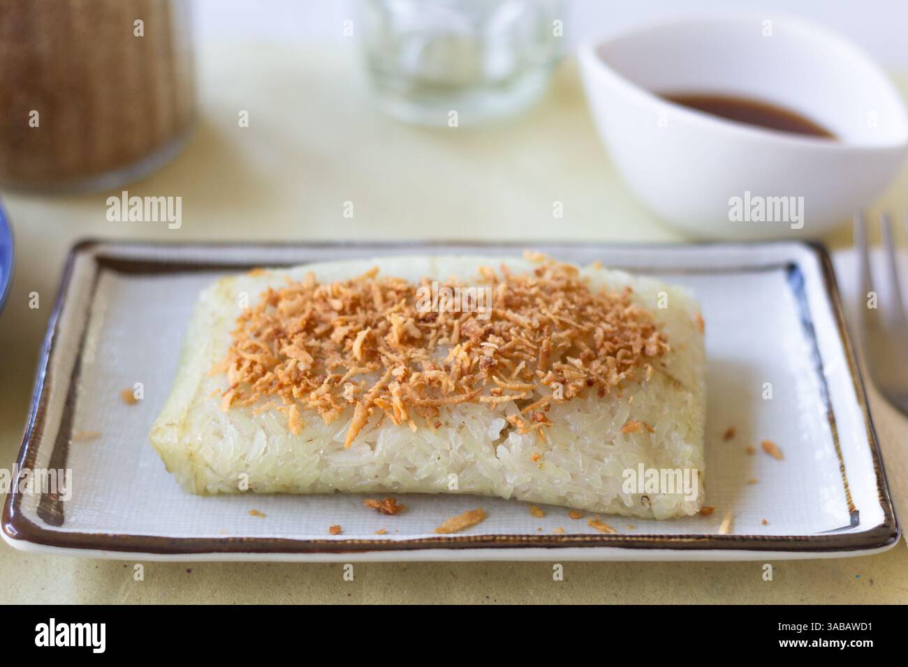 Suman fatto di riso appiccicoso condito con noce di cocco essiccato dolce servito in un caffè locale a Batangas, Filippine Foto Stock