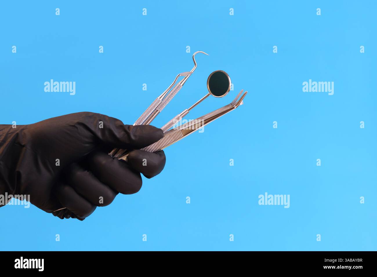 Strumento dentale nelle mani di un dentista, primo piano. Specchio dentale, pinzette e ganci utilizzati nel trattamento di varie malattie dei denti e GU Foto Stock