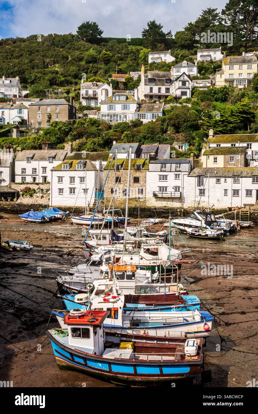 Barche da pesca con bassa marea nel porto di Polperro, con case tradizionali che sorgono sulle colline. Foto Stock