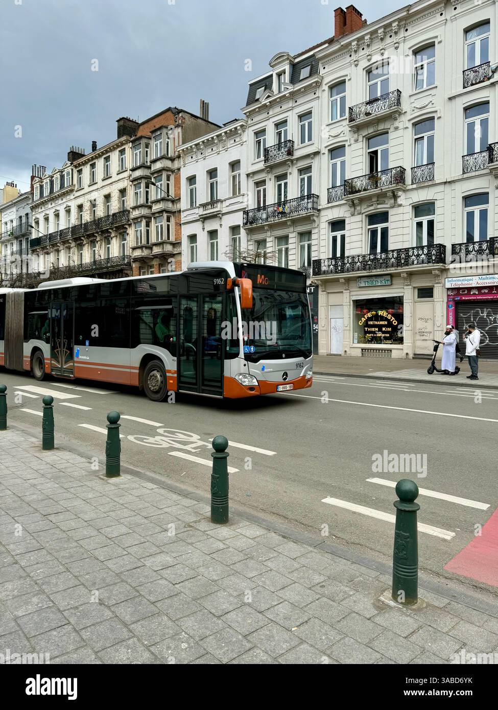 Un autobus cittadino che guida attraverso le vivaci strade di Bruxelles, con edifici moderni e monumenti architettonici sullo sfondo. Foto Stock