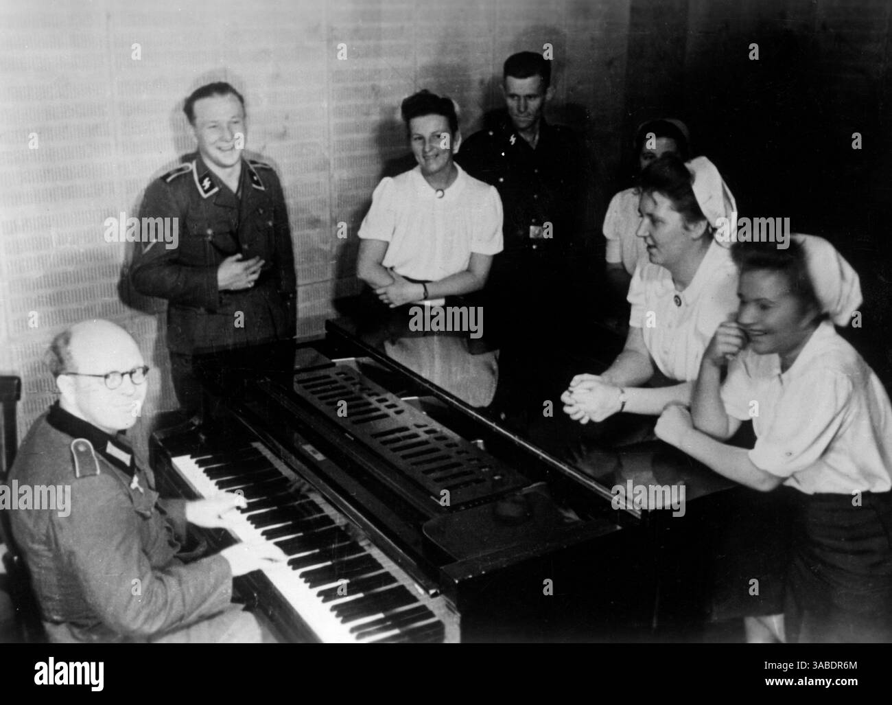 Gli infermieri DRK visitano la stazione radio dei soldati a Belgrado. Un soldato della Wehrmacht suona al pianoforte a coda, sullo sfondo due membri delle Waffen SS. Foto: Homann [traduzione automatizzata] Foto Stock