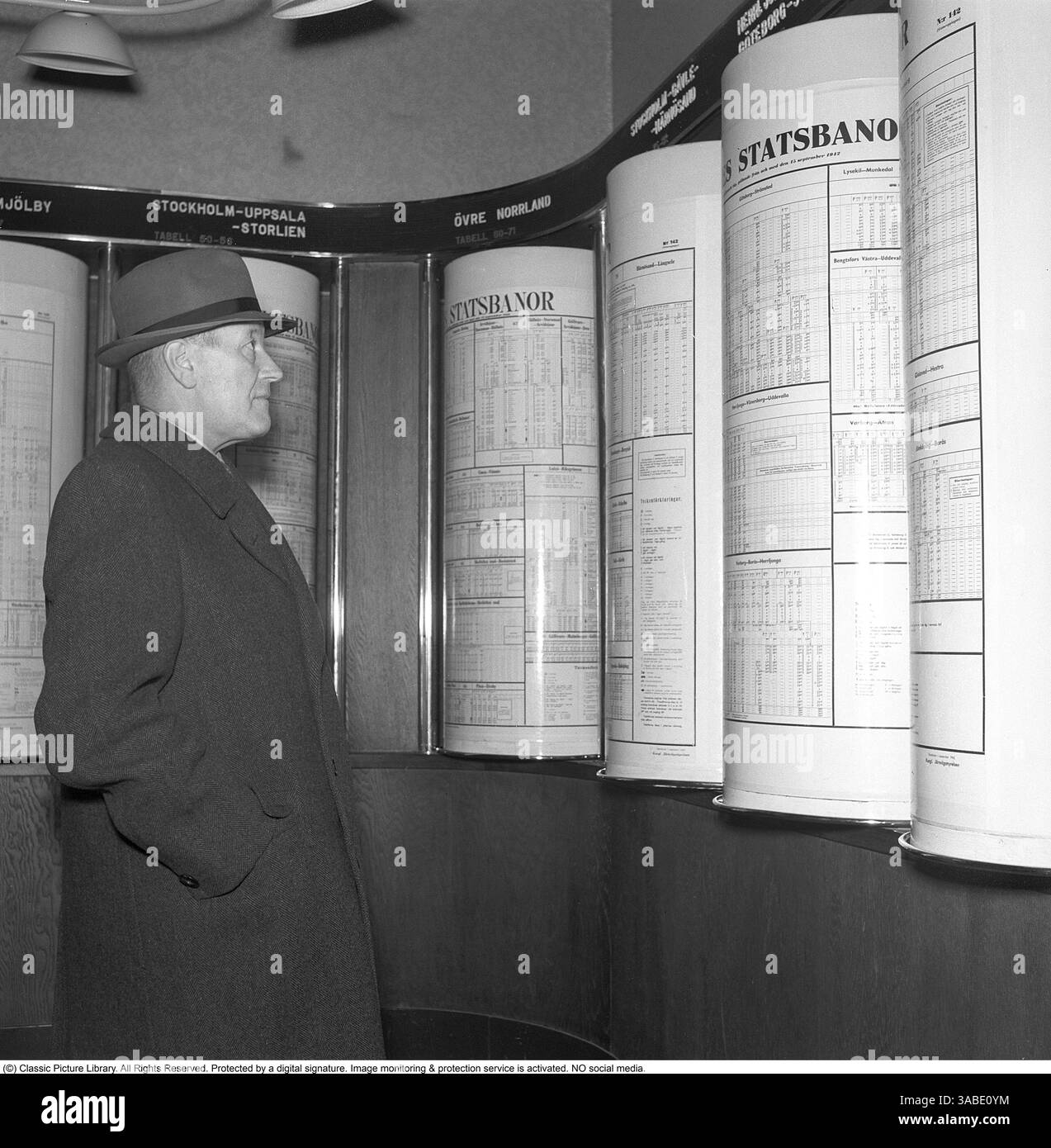 Stazione centrale di Stoccolma 1942. Nella sala d'attesa della stazione ferroviaria un uomo si trova di fronte agli orari che informano sugli orari di arrivo e di partenza dei treni. Sopra ogni orario è indicato in quale direzione vanno i treni. La costruzione è originale con gli orari montati su rulli che potrebbero quindi essere ruotati. Kristoffersson rif. A129-1 Foto Stock