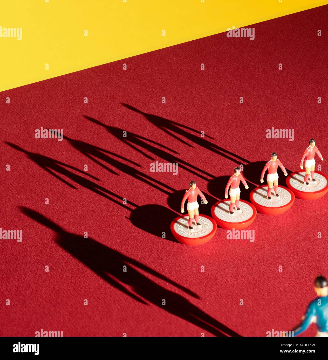 Membri del team Subbuteo rosso e bianco degli anni '1970 con lunghe ombre su sfondo rosso Foto Stock