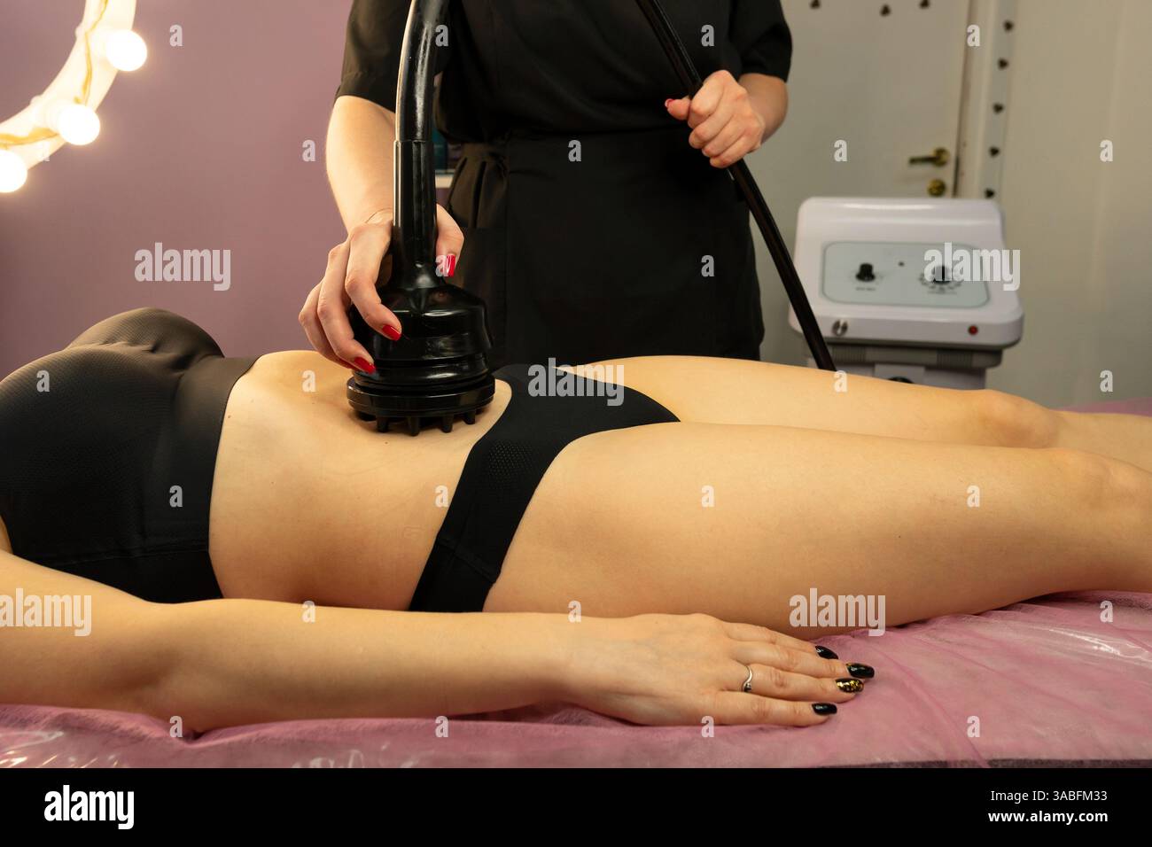 Lo specialista dei guanti applica il trattamento di cavitazione all'area addominale. Prevenzione della cellulite, ripristino del tono muscolare e drenaggio linfatico Foto Stock