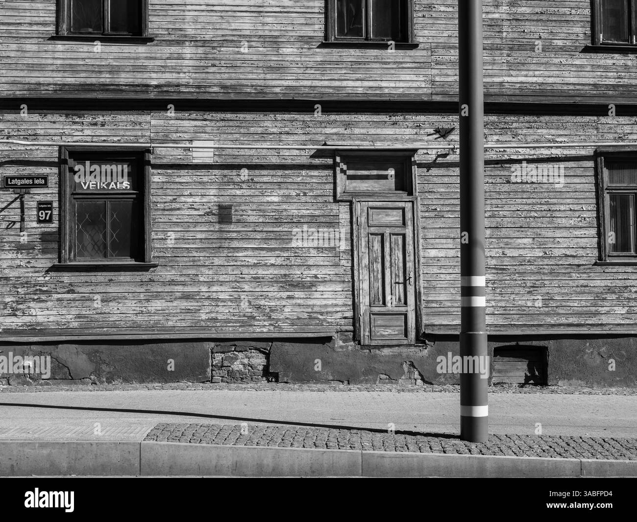 Vecchio edificio in legno con una porta e finestre in bianco e nero. Foto Stock