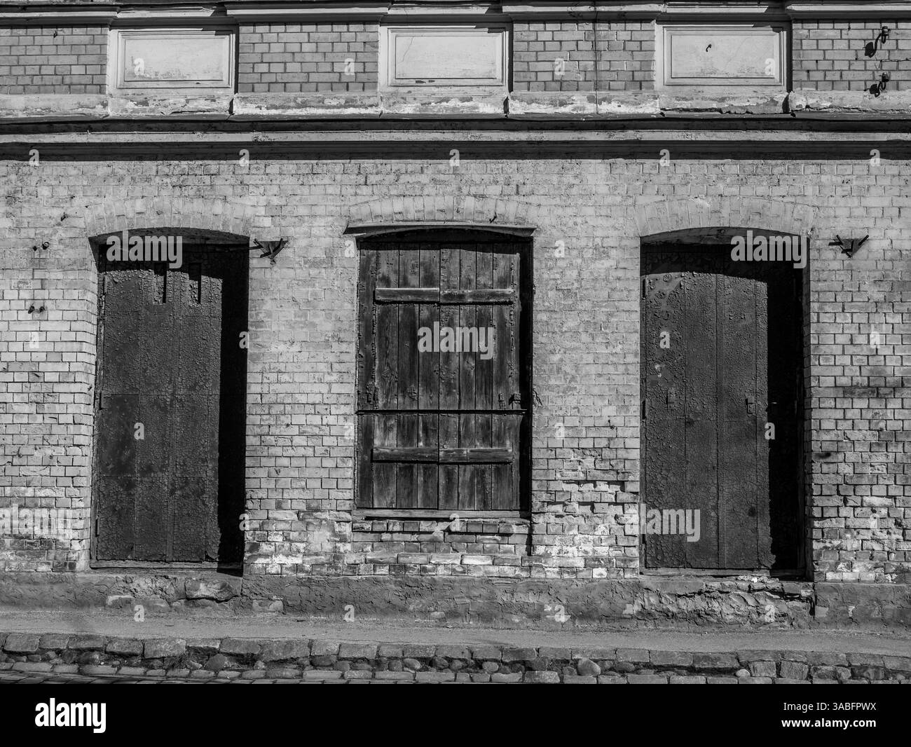 Vecchio edificio in mattoni con porte in legno intemperie alla luce calda del sole. Foto Stock