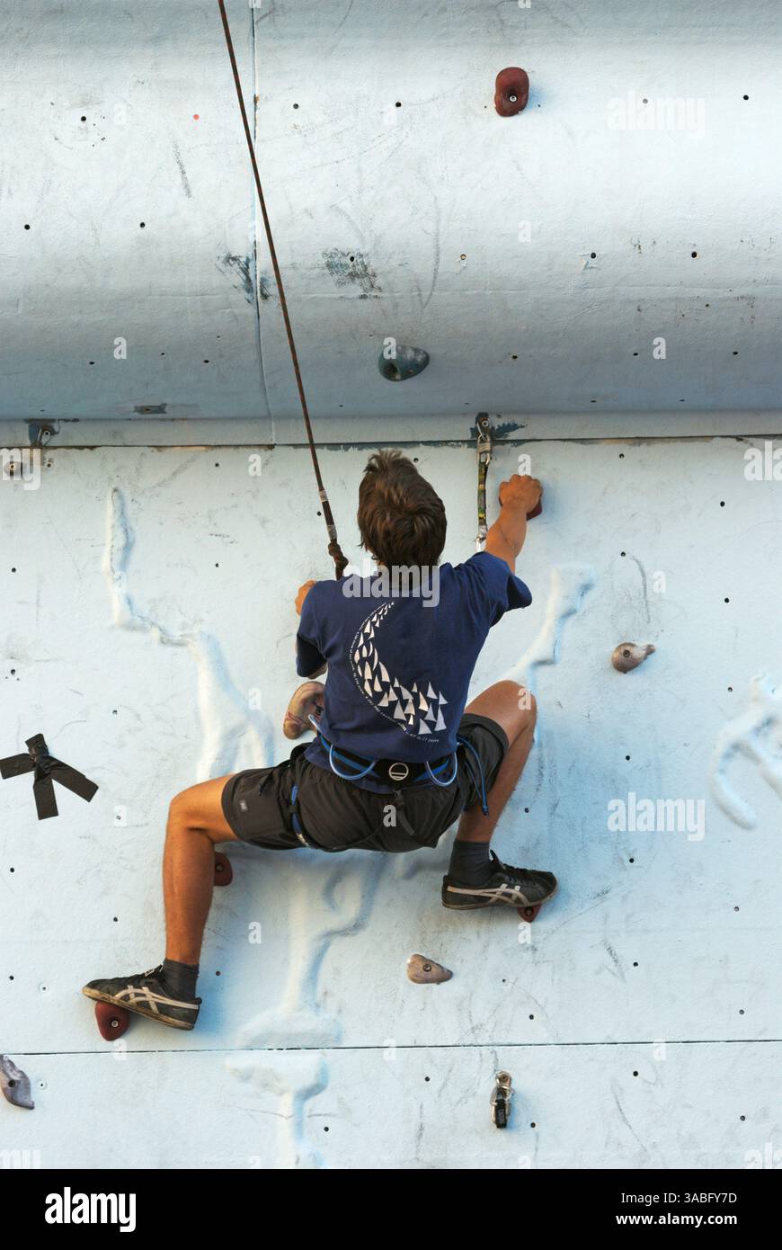 un alpinista maschio che pratica l'arrampicata su una parete di roccia artificiale Foto Stock