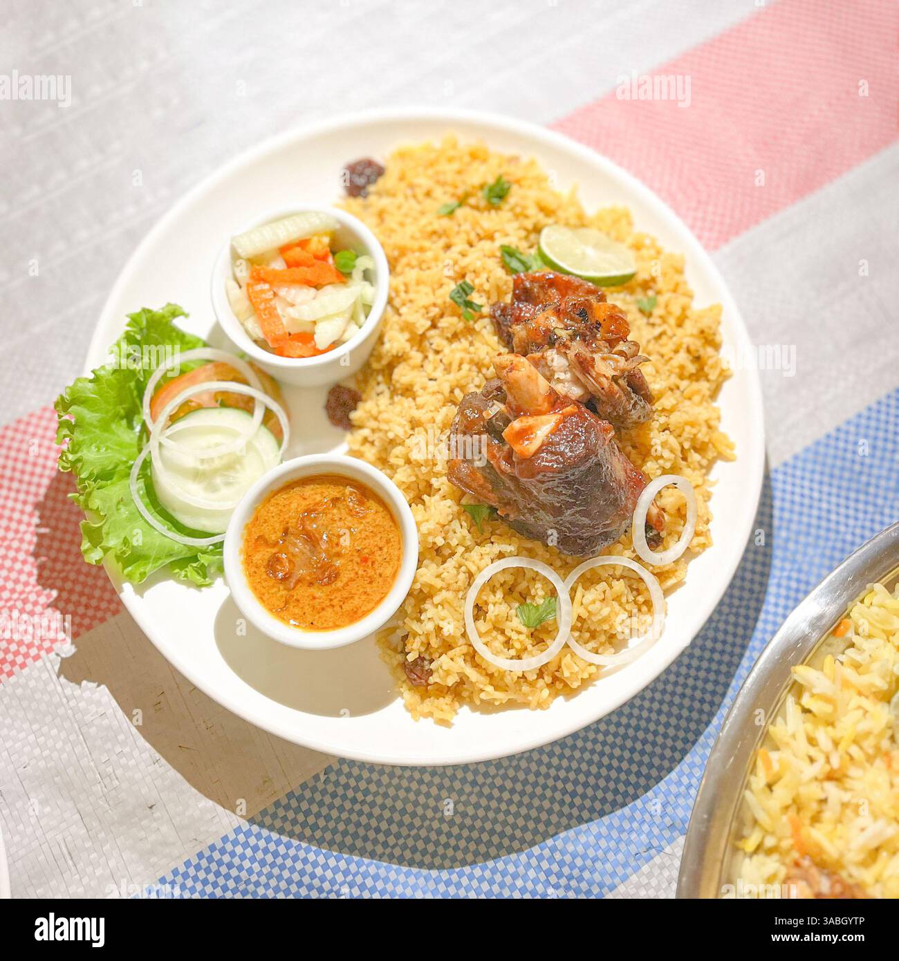 Vista dall'alto del riso Biryani servito con carne, sottaceti e curry deliziosi - Immagine stock catturata con smartphone