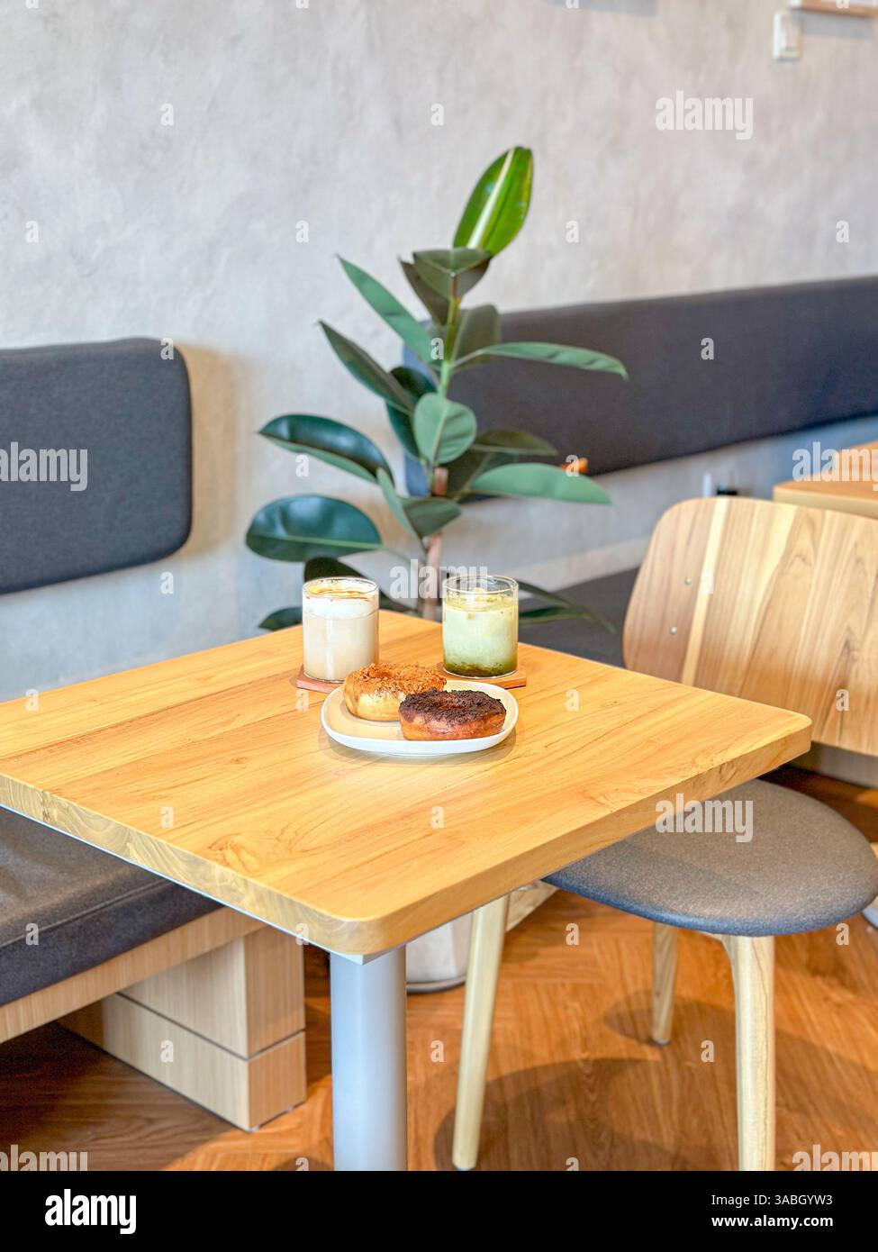 caffè ghiacciato e ciambelle serviti su un tavolo di legno con sfondo caffetteria - Immagine stock catturata con smartphone