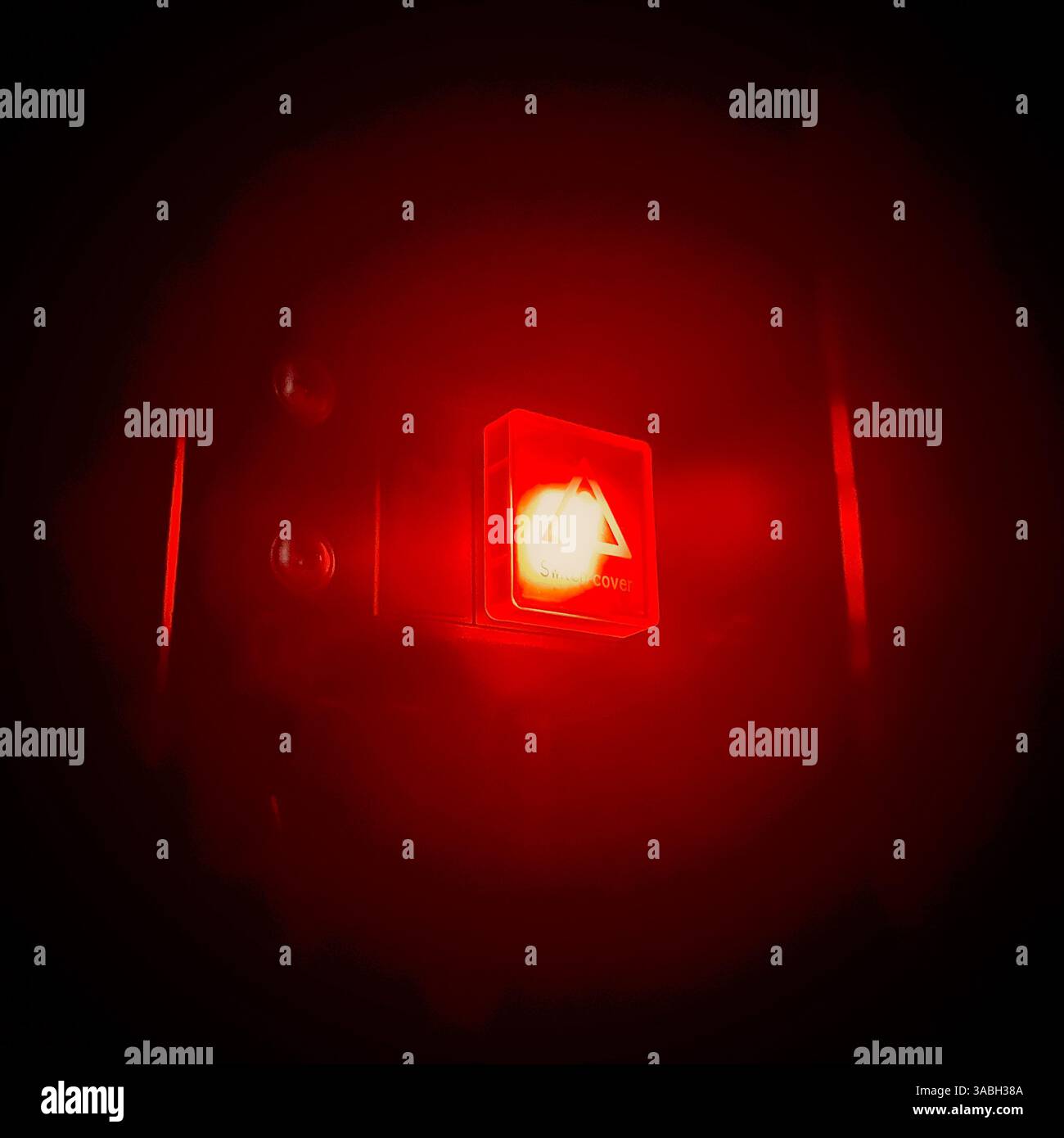 vista ravvicinata di un pulsante con una luce rossa brillante sullo sfondo scuro - Immagine stock catturata con smartphone
