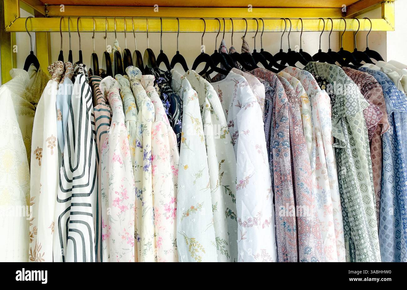 Primo piano di camicie colorate appese al rack nel negozio di moda Foto Stock