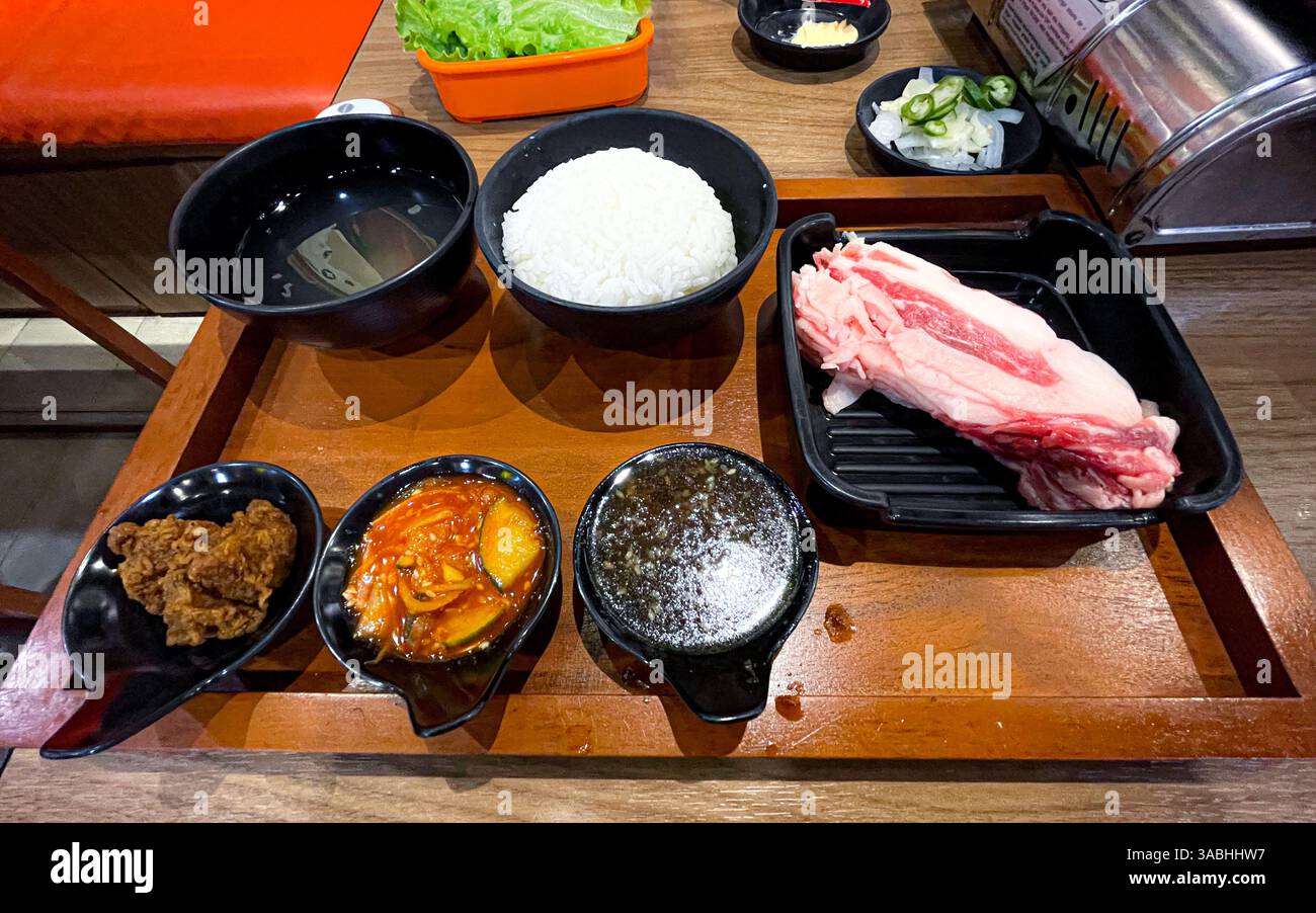 Vista dall'alto dei set combo barbecue alla griglia coreani sul tavolo della griglia, kimchi, zuppa, pancetta, pollo croccante, salsa di riso e piatti di sottaceti - Immagine stock catturata con smartphone