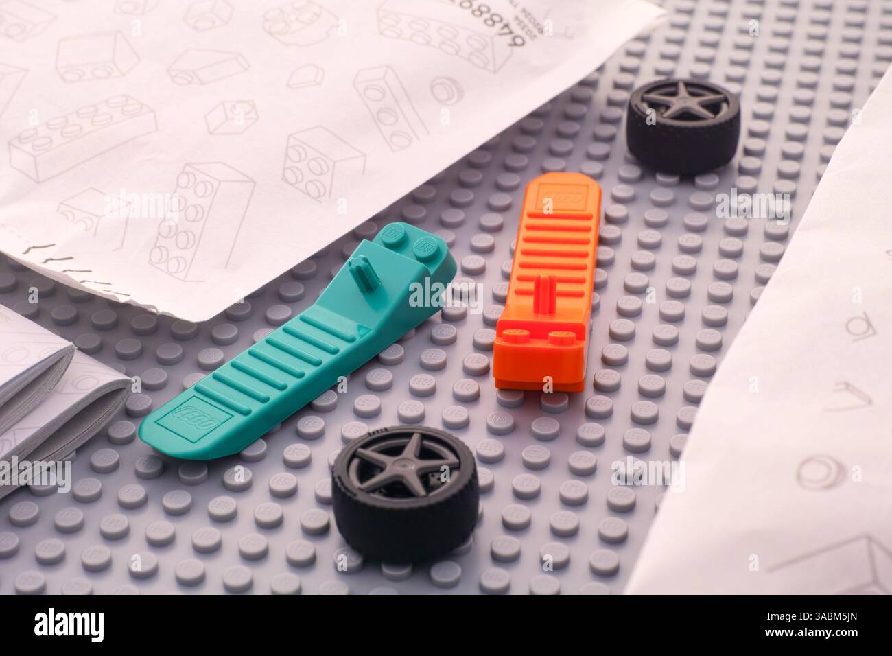 Tambov, Federazione Russa - 22 giugno 2024 due separatori di mattoni LEGO e due ruote poste tra sacchetti di carta con pezzi LEGO su una base grigia Foto Stock