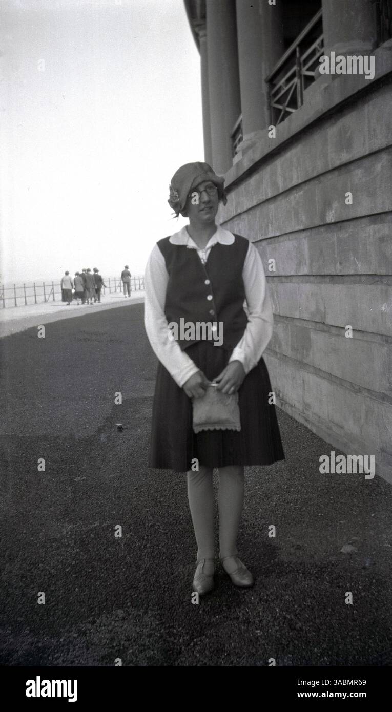Anni '1930, storica moda femminile dell'epoca, una giovane donna in piedi per la sua foto sulla costa, cappello e in mano una piccola borsa o borsa, Inghilterra, Regno Unito. Foto Stock