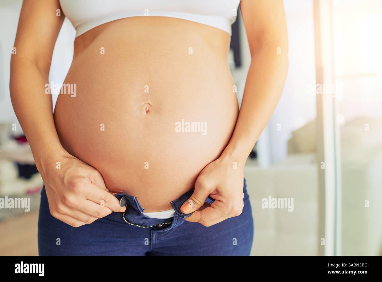 Incinta, donna e stomaco con fit di pantaloni per maternità, lotta crescita del bambino nella pancia. Mani, persona difficile e donna con jeans stretti a. Foto Stock
