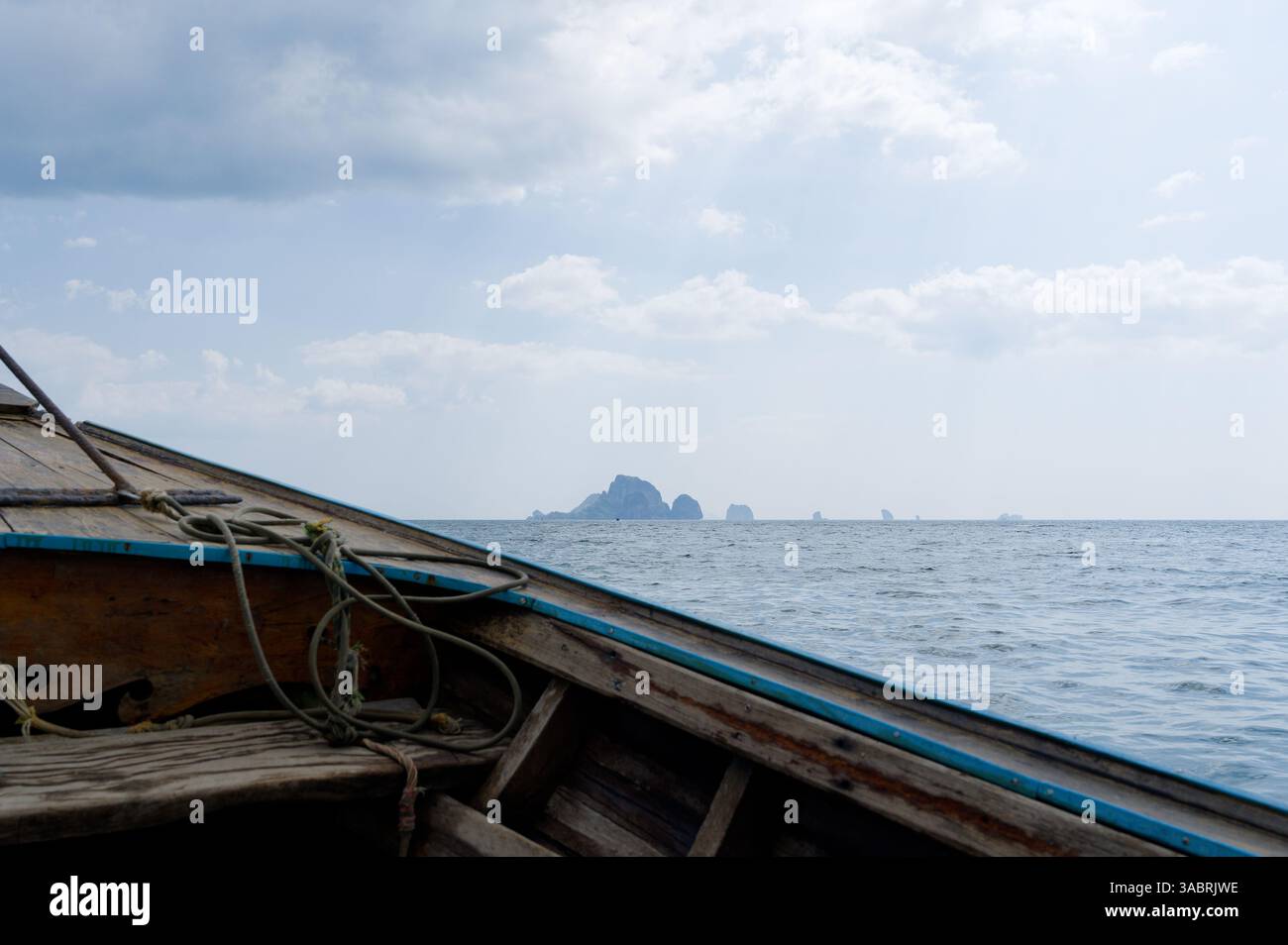 La barca a coda lunga si dirige verso le lontane isole calcaree sotto un nebbioso cielo del Mare delle Andamane Foto Stock