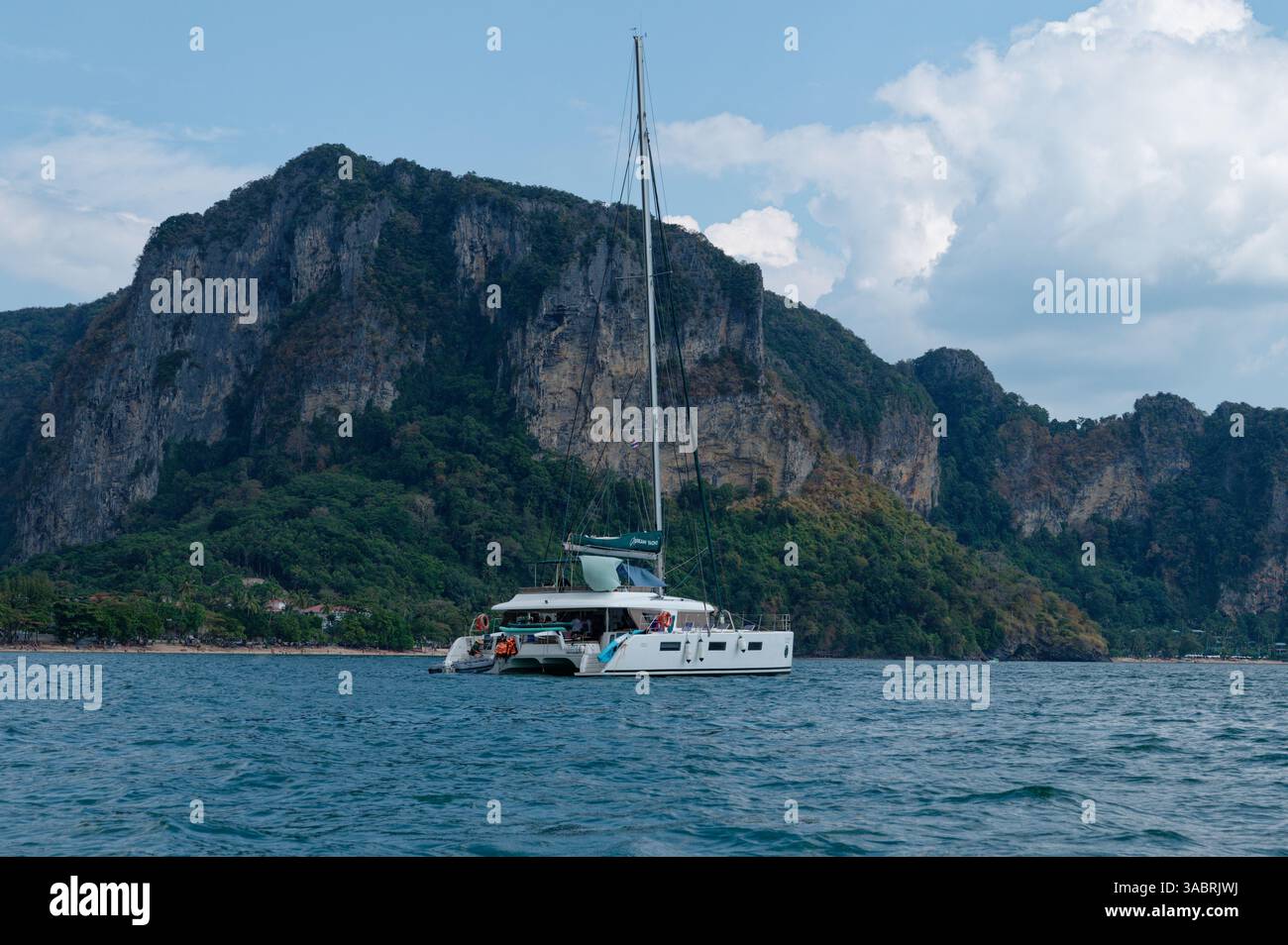 Il catamarano si trova al largo della lussureggiante costa di Krabi, circondato da torreggianti scogliere e mare tranquillo Foto Stock