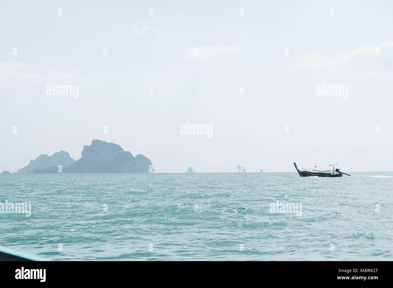 Barca a coda lunga che naviga attraverso le acque turchesi di Krabi con isole calcaree all'orizzonte Foto Stock