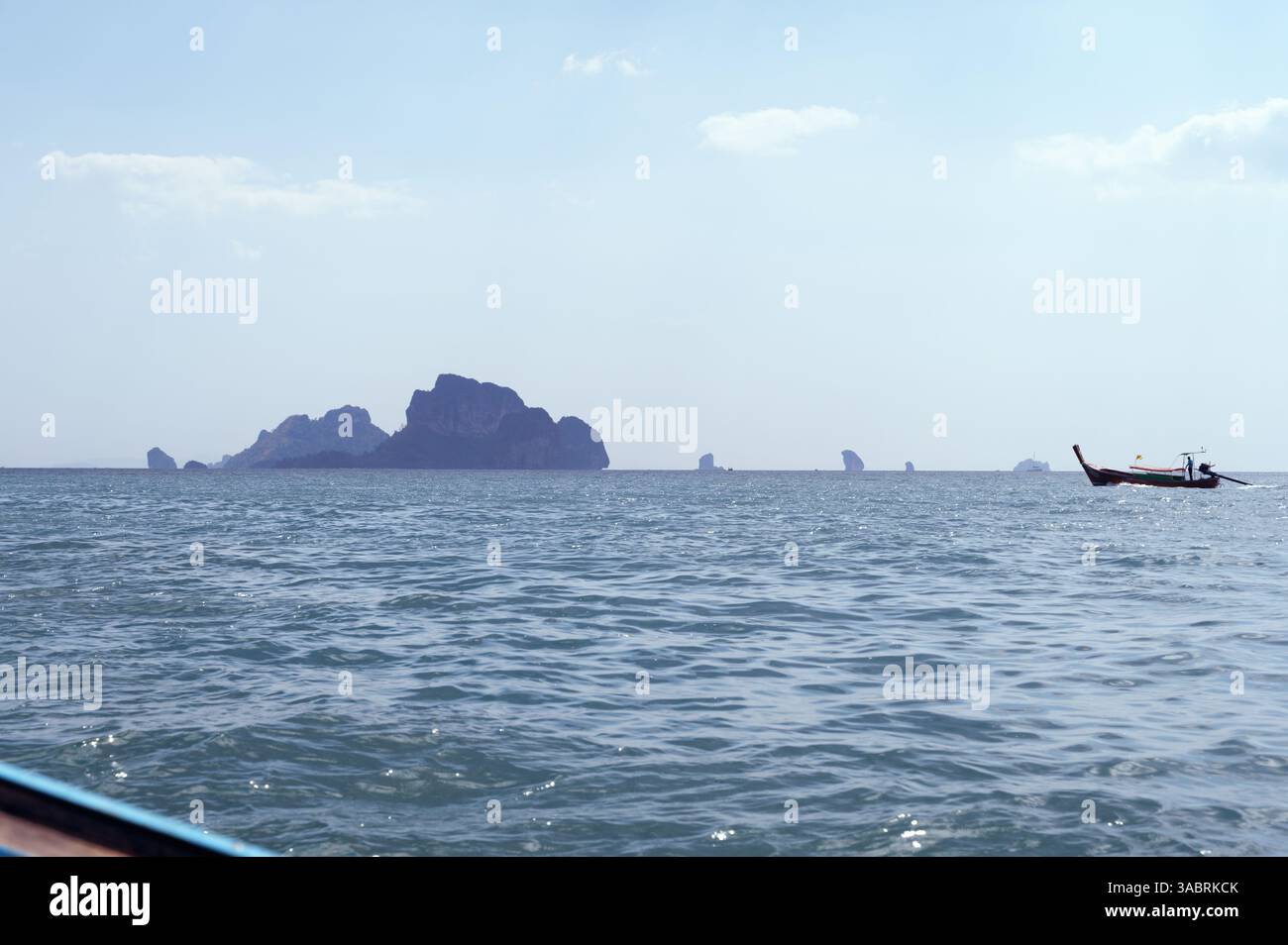 Barca a coda lunga che naviga attraverso le acque di Krabi con isole calcaree in lontananza Foto Stock
