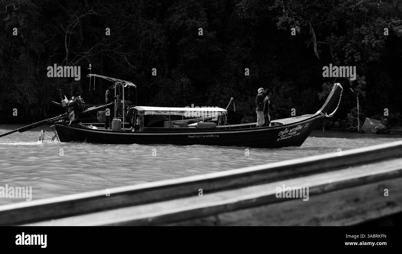 Una barca a coda lunga galleggia tranquillamente vicino alle coste boschive di Tonsai Foto Stock