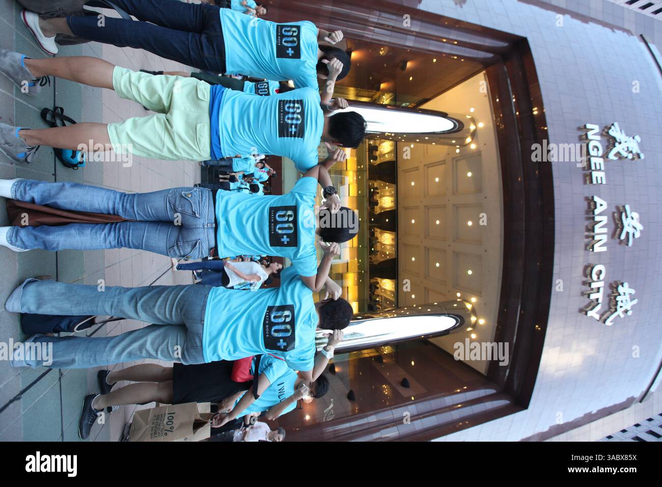 Vista verticale, gruppo di persone in posa. Earth Hour riunisce individui, comunità e imprese per aiutare a ripristinare la nostra Terra. Singapore. Foto Stock