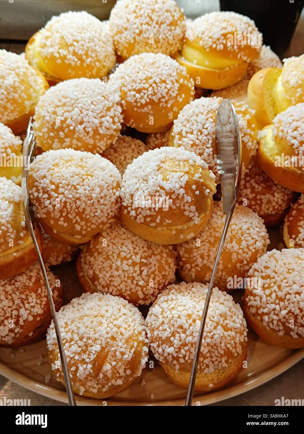 Primo piano di una pila di ciambelle dorate ricoperte di zucchero perlato. Foto Stock