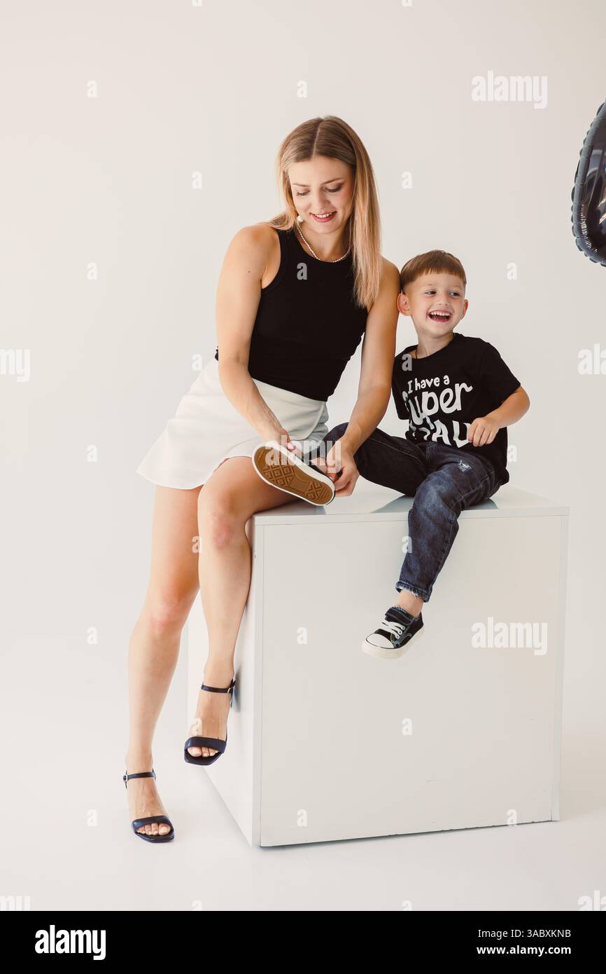 Un momento di gioia cattura una madre e un figlio in uno studio luminoso, mostrando il loro legame amorevole attraverso sorrisi e risate sentiti, creando un braccio del cuore Foto Stock