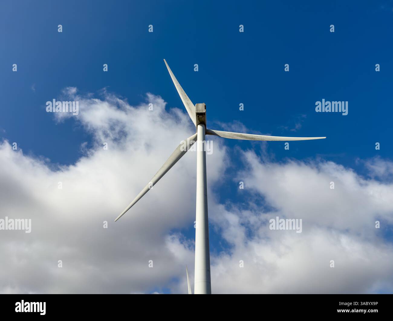 Turbina eolica vista contro un cielo blu nuvoloso in una giornata di sole nel Regno Unito. Foto Stock
