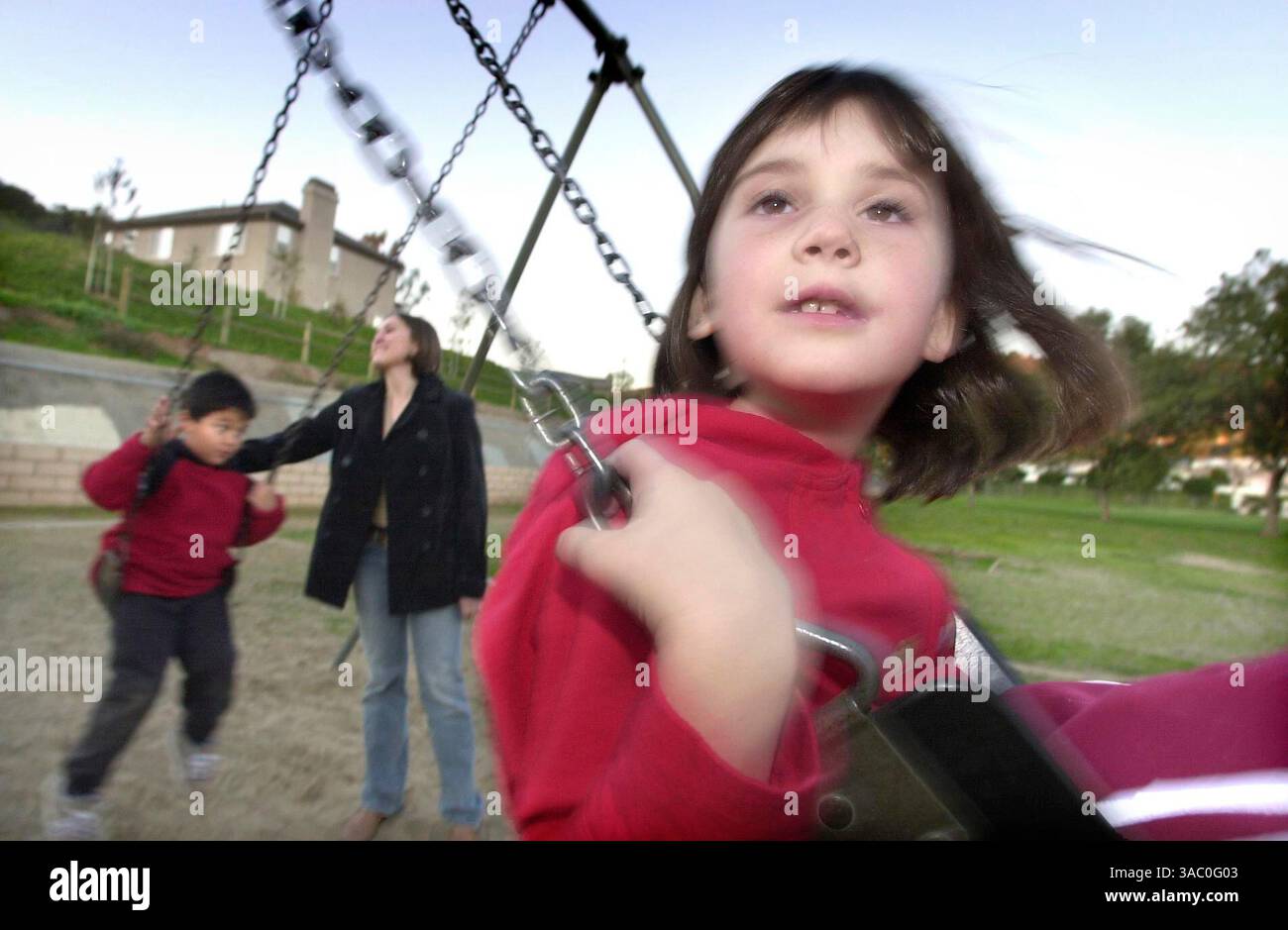 (Pubblicato il 12/12/2004, N-6) la bambina autistica MAISY DONOVAN (Maisie) gioca sulle altalene alla Richland Elementary School nel tardo pomeriggio. A sinistra c'è il bambino autistico CHRISTOPHER BUMANGLAG (cq) sulle altalene accompagnato anche da VERONICA FREEMEL (cq), uno dei bambini autistici qui presenti. FOTO U/T CHARLIE NEUMAN Foto Stock