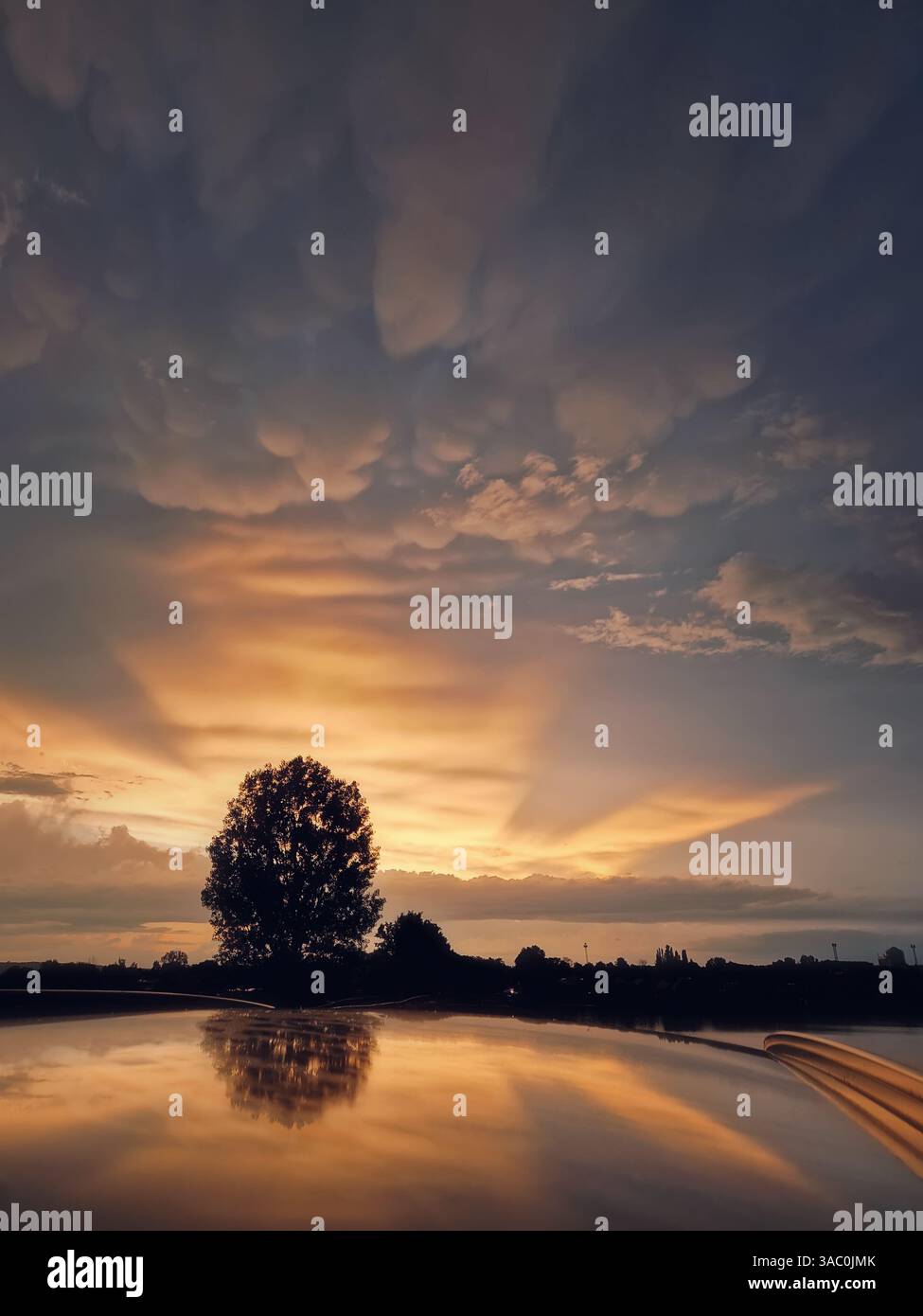 Dopo la tempesta, con i raggi del tramonto che piergono le meravigliose nuvole di Mammatus - Immagine stock catturata con smartphone