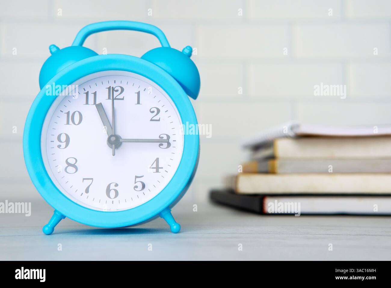 Una sveglia blu e una pila di libri. Gestione del tempo, concetto di studio. Foto Stock