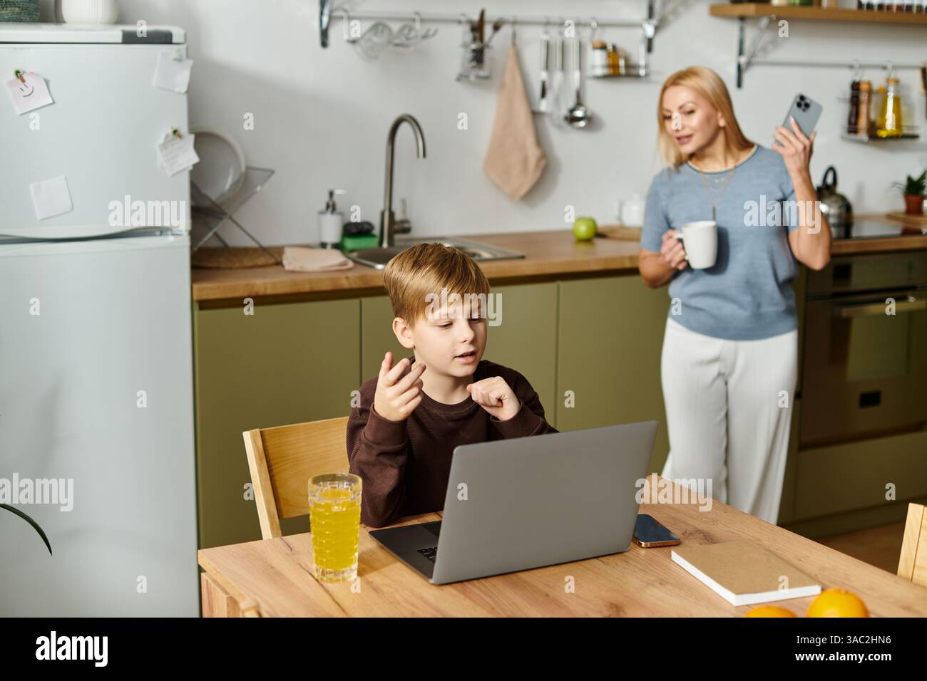Una madre si impegna con suo figlio mentre esplora il suo portatile, creando un'atmosfera calda e giocosa. Foto Stock