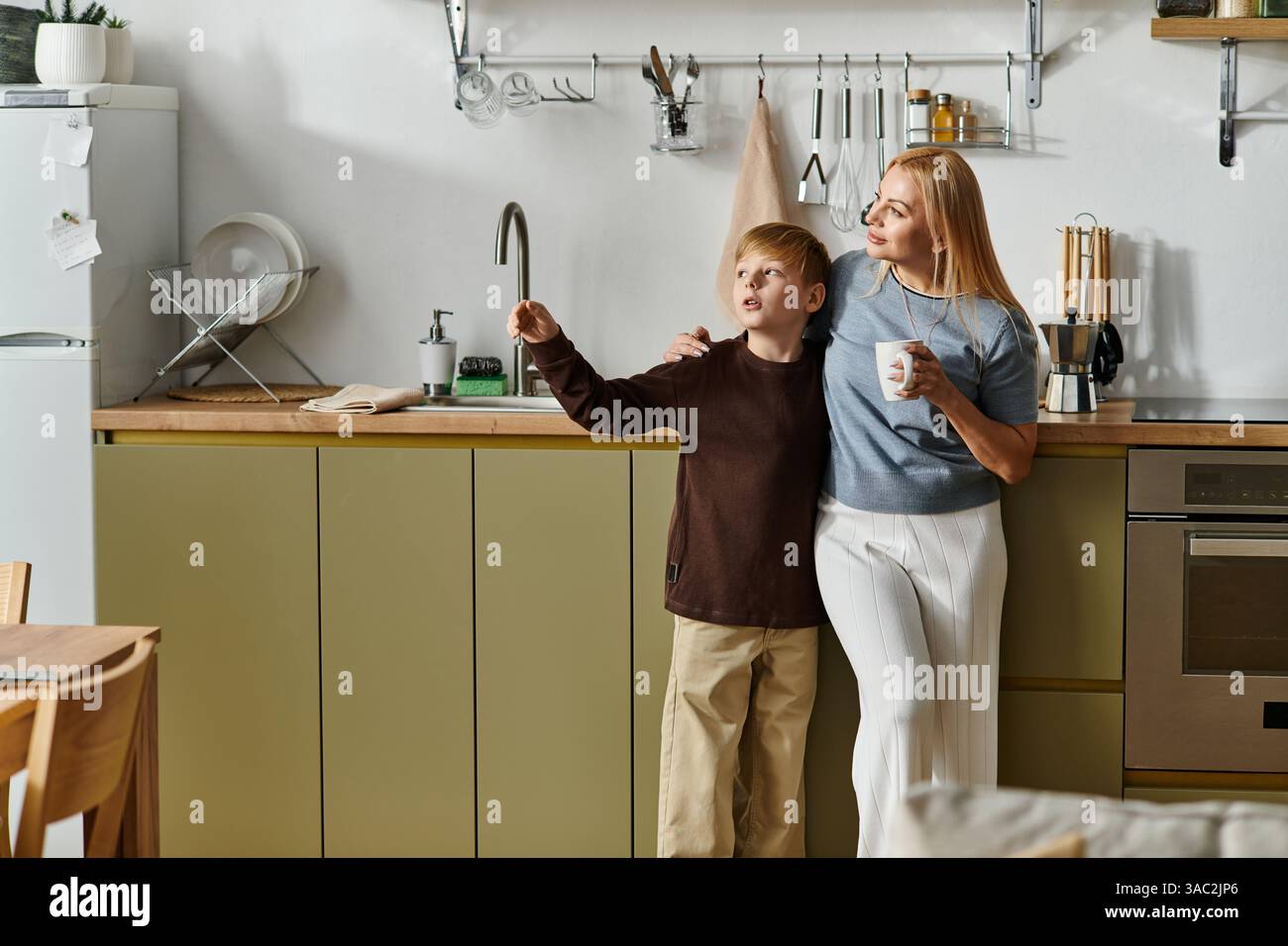 Una madre e un figlio condividono un momento tenero nella loro elegante cucina, legandosi sulle meraviglie della vita. Foto Stock