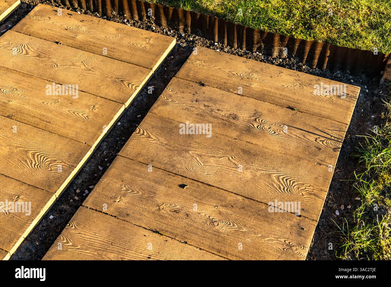Lastre di pietra che ricordano tavole di legno sulla terrazza, che posano il pavimento sotto il pergolato nel giardino, costruiscono una veranda con giardino Foto Stock