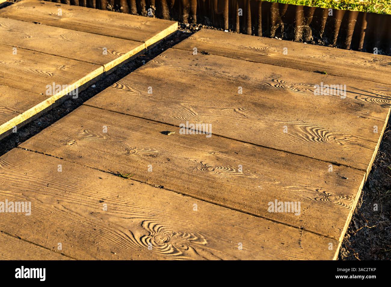 Lastre di pietra che ricordano tavole di legno sulla terrazza, che posano il pavimento sotto il pergolato nel giardino, costruiscono una veranda con giardino Foto Stock