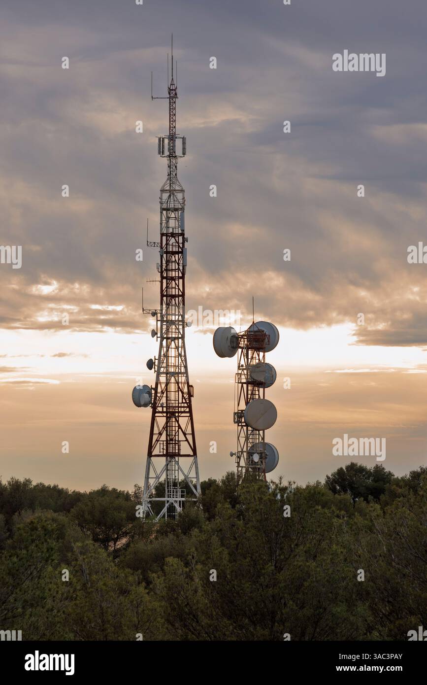 Grandes torres de telecomunicaciones en lo alto de Montañas al atardecer Foto Stock